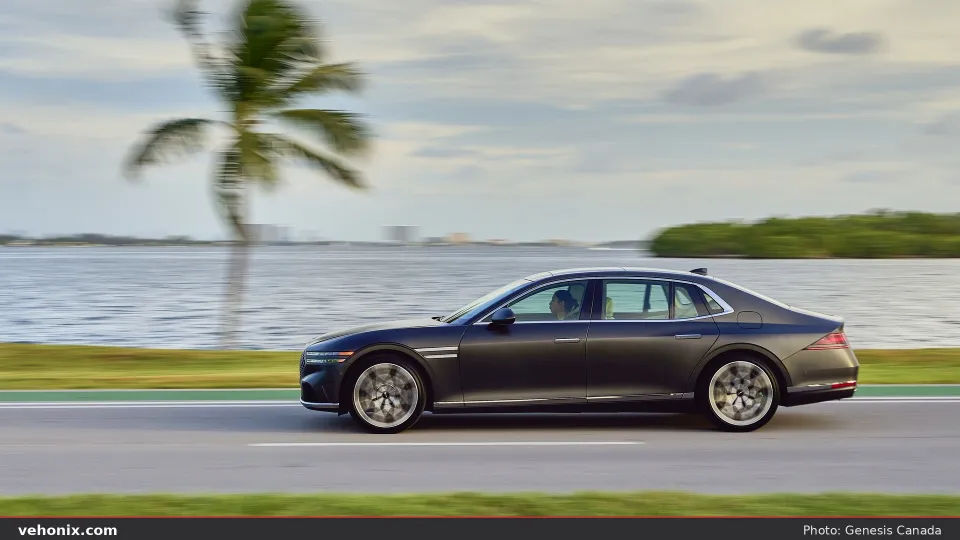 2026 Genesis G90 in dark paint, side profile in motion past water and palm trees