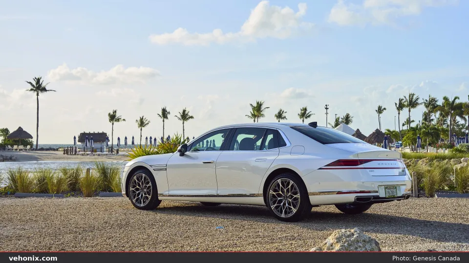 2026 Genesis G90 in white, rear three-quarter parked near a beach with palm trees
