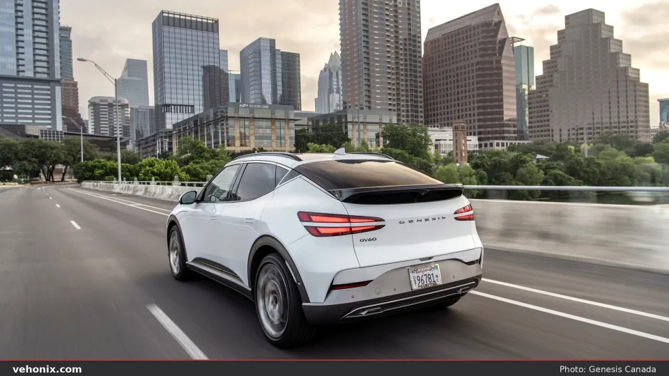 2026 Genesis GV60 Advanced in white, rear three-quarter on an urban highway