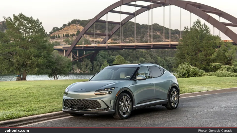 2026 Genesis GV60 in light blue, front three-quarter near an arched bridge