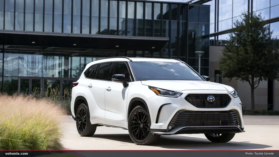 2026 Toyota Highlander XSE in white, front three-quarter view by a glass building