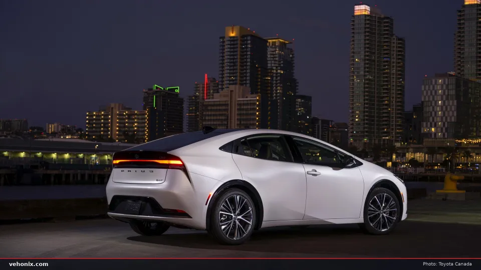 2026 Toyota Prius Limited in white, rear three-quarter view with city lights at dusk
