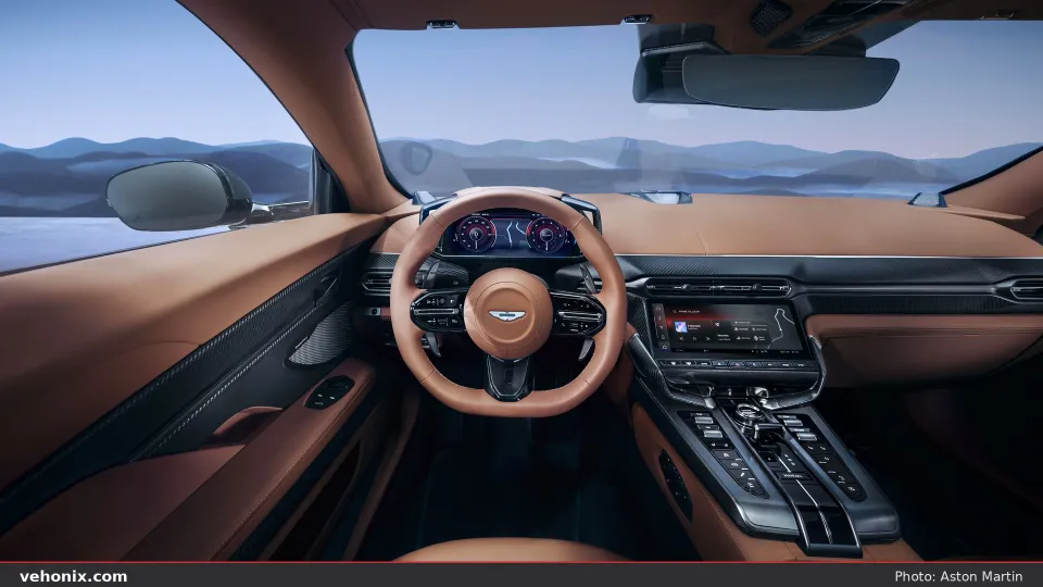 2026 Aston Martin Vanquish cockpit with tan leather steering wheel and dual digital screens