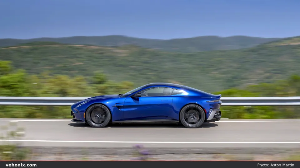 2026 Aston Martin Vantage in Ion Blue, side profile driving past green hills