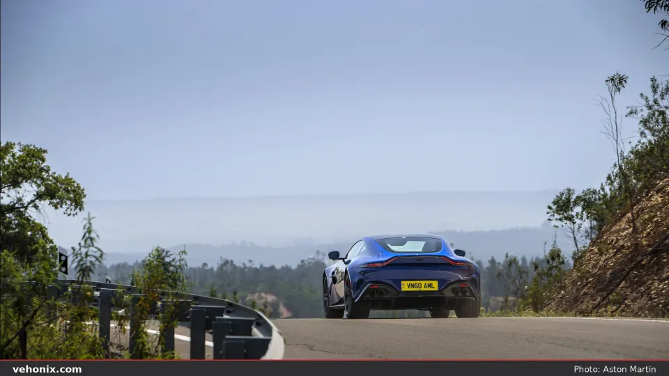 2026 Aston Martin Vantage in Ion Blue, rear view driving on a mountain road above a valley