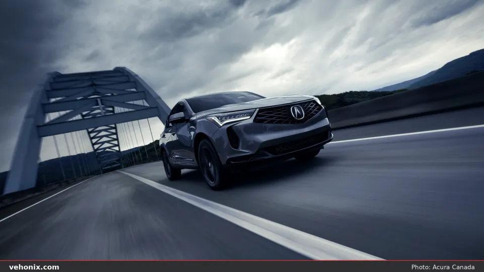 2026 Acura RDX SH-AWD A-SPEC front three-quarter view driving across a bridge