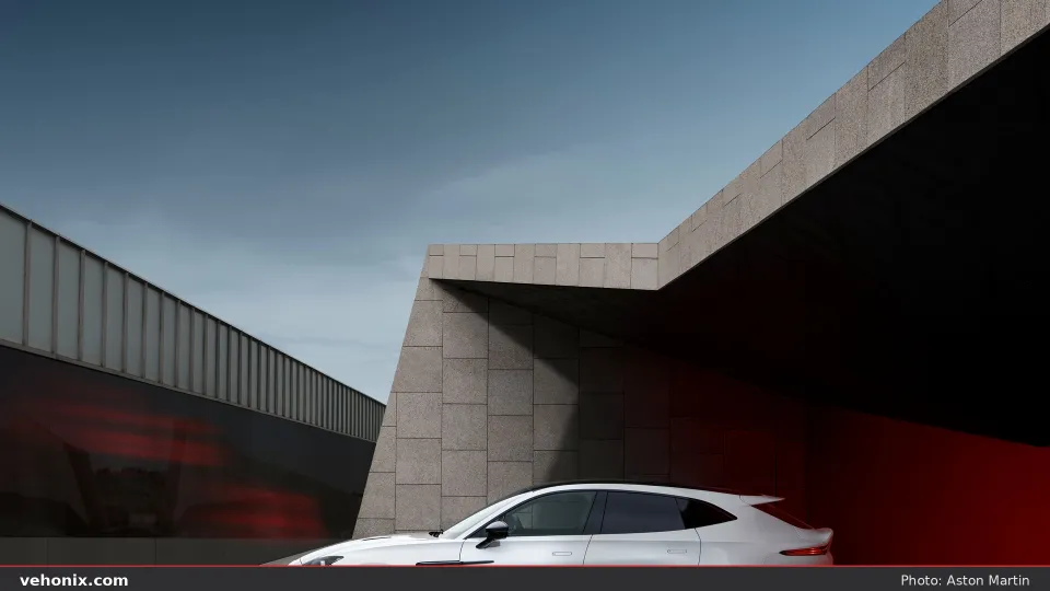 2026 Aston Martin DBX S in white, partial side view beside modern architecture
