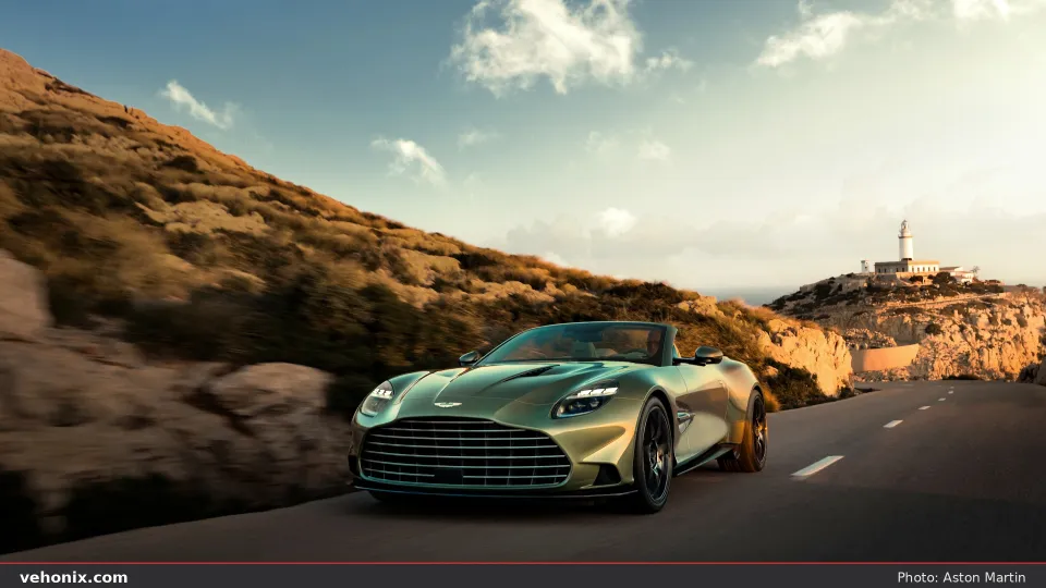 2026 Aston Martin Vanquish Volante in sage green, front three-quarter on a coastal road