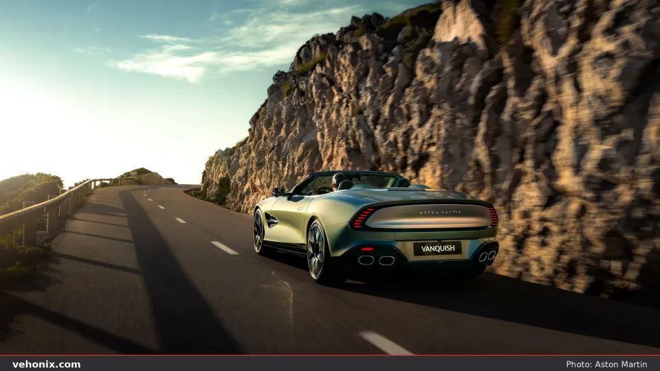 2026 Aston Martin Vanquish Volante in sage green, rear three-quarter on a coastal cliff road