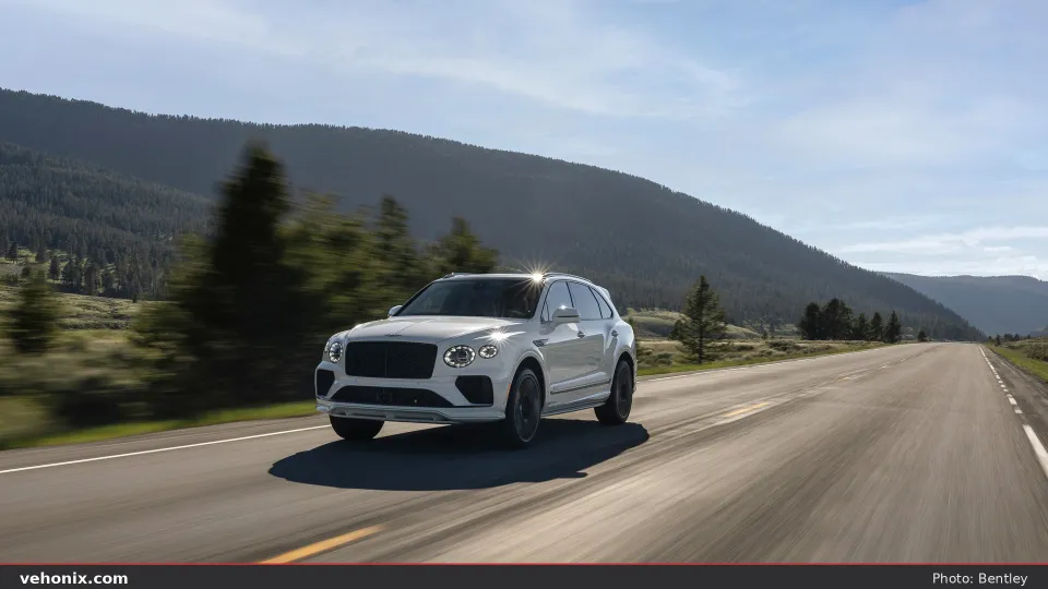 2026 Bentley Bentayga in white, front three-quarter driving on a mountain road