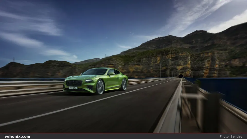 2026 Bentley Continental GT in metallic green driving on a mountain bridge