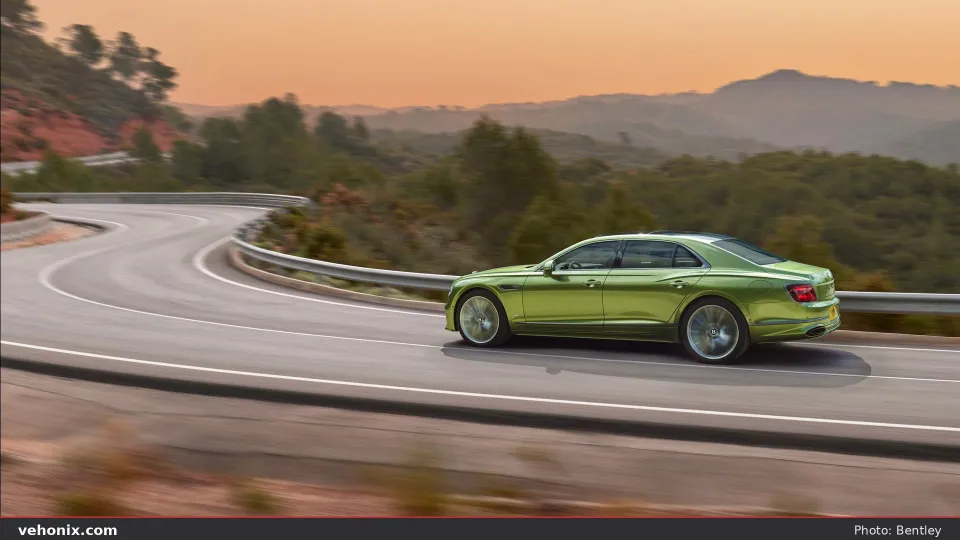 2026 Bentley Flying Spur in metallic green on a mountain road at dusk