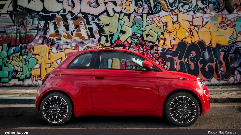 2026 Fiat 500e (RED) in red, full side profile against a graffiti wall