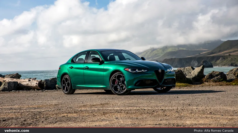 2026 Alfa Romeo Giulia Veloce in metallic green, front three-quarter view beside rocky coast