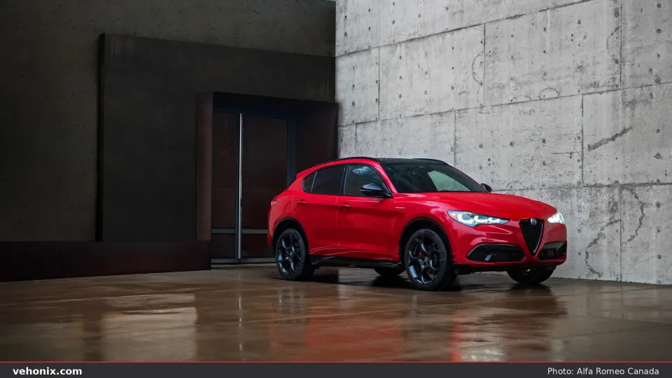 2026 Alfa Romeo Stelvio Veloce in red, front three-quarter view on wet courtyard pavement