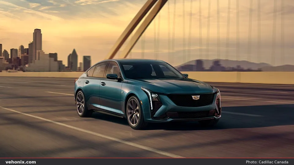 2026 Cadillac CT5 in teal, front three-quarter driving on a bridge at golden hour