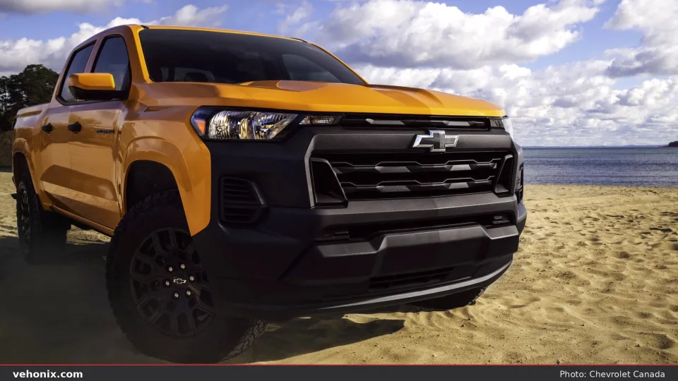 2026 Chevrolet Colorado in orange, front three-quarter on a sandy beach