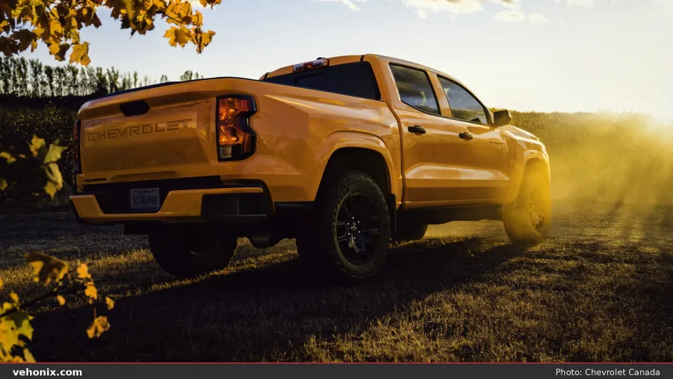 2026 Chevrolet Colorado in yellow, rear three-quarter in a grassy field at sunset