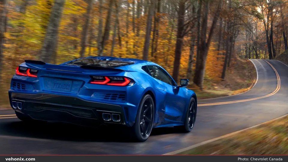 2026 Chevrolet Corvette E-Ray in blue, rear three-quarter view on a forest road