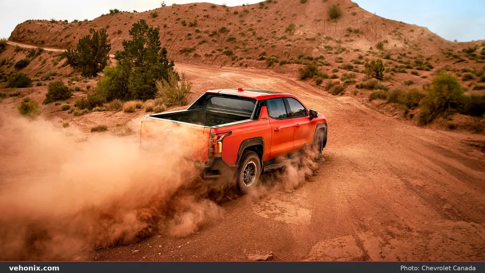 2026 Chevrolet Silverado EV in red, rear three-quarter kicking up desert dust