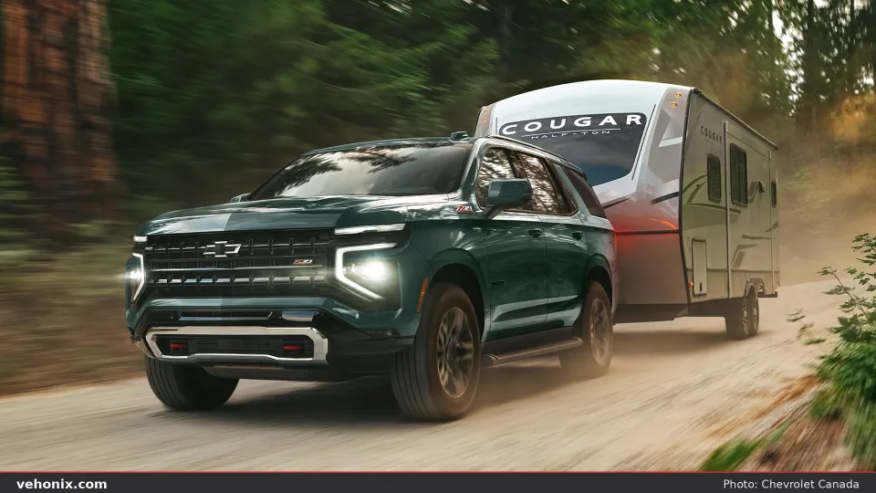 2026 Chevrolet Tahoe in green, front three-quarter view towing a trailer