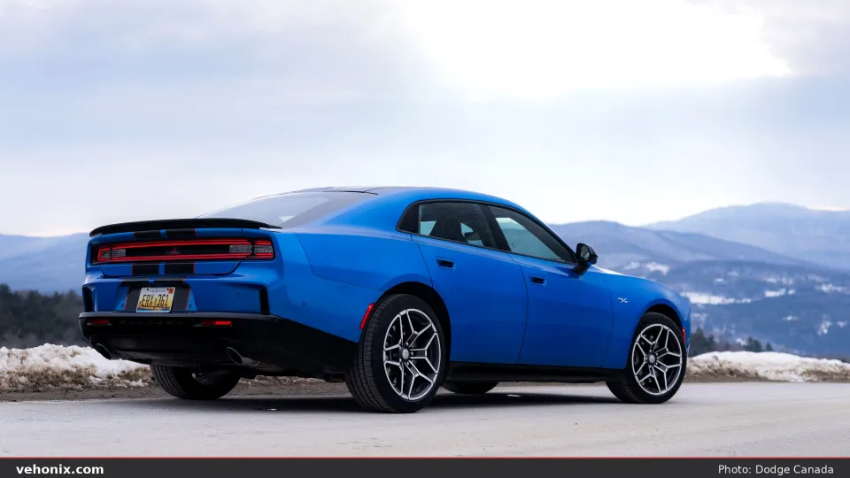 2026 Dodge Charger R/T in blue with black stripes, rear three-quarter on a mountain road