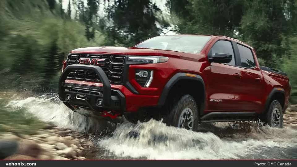 2026 GMC Canyon AT4X AEV in red fording a rocky stream off-road