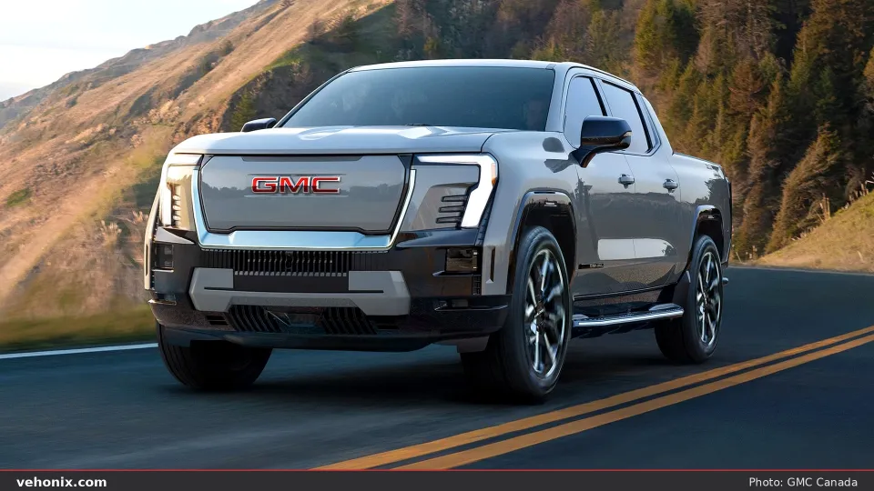 2026 GMC Sierra EV Denali in grey, front three-quarter on a mountain road