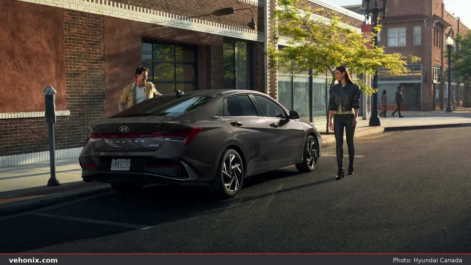 2026 Hyundai Elantra Hybrid in dark grey, rear three-quarter at sunset downtown