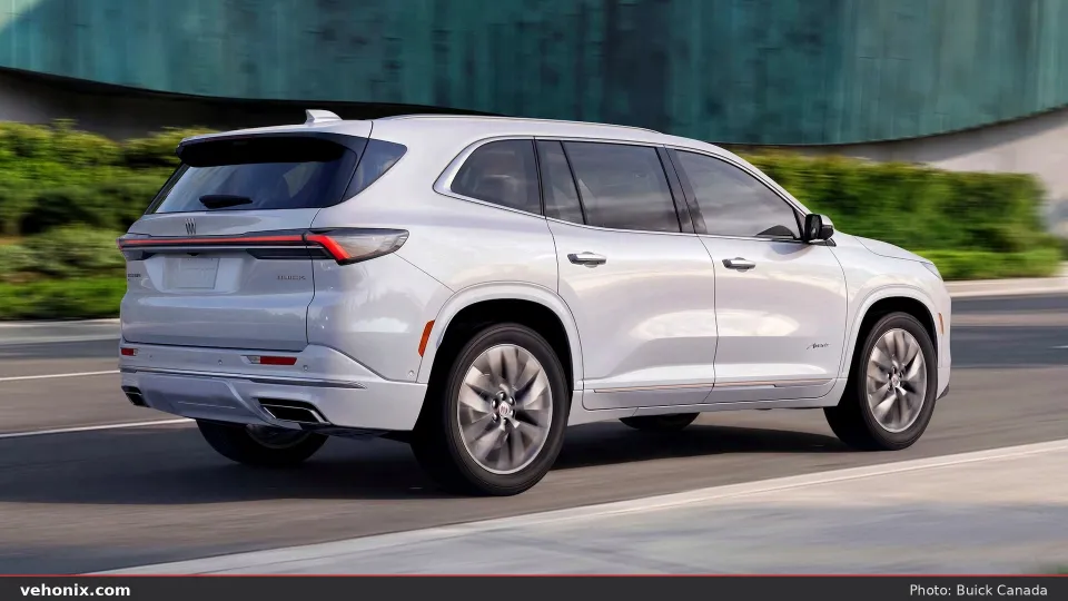2026 Buick Enclave in white, rear three-quarter view driving on a paved road