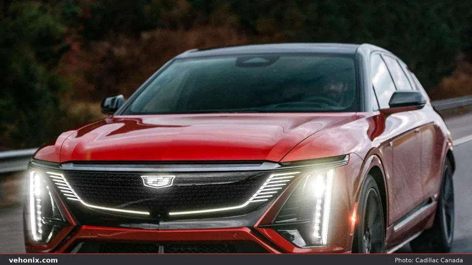 2026 Cadillac LYRIQ-V in red, front three-quarter driving with illuminated grille