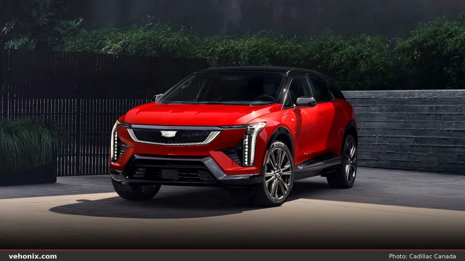2026 Cadillac OPTIQ in red, front three-quarter parked by tropical foliage