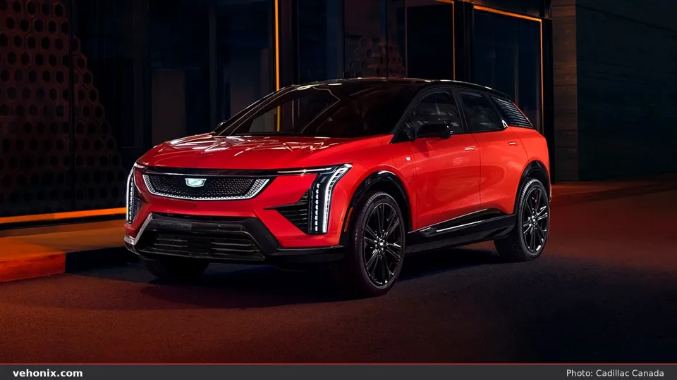 2026 Cadillac OPTIQ in red, front three-quarter parked on a city street at night