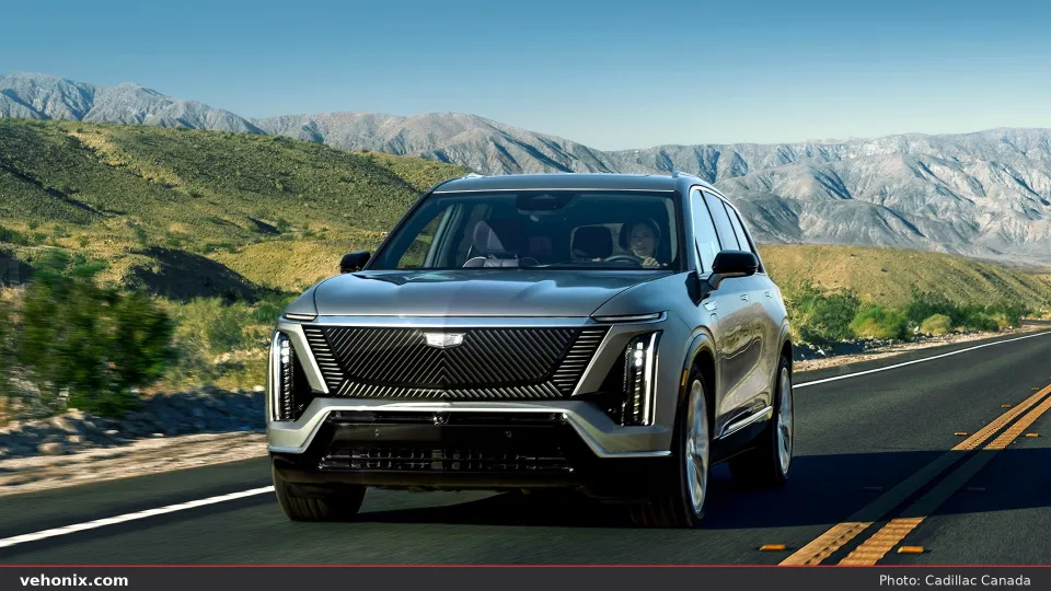 2026 Cadillac VISTIQ in silver, head-on driving on a desert highway under blue sky