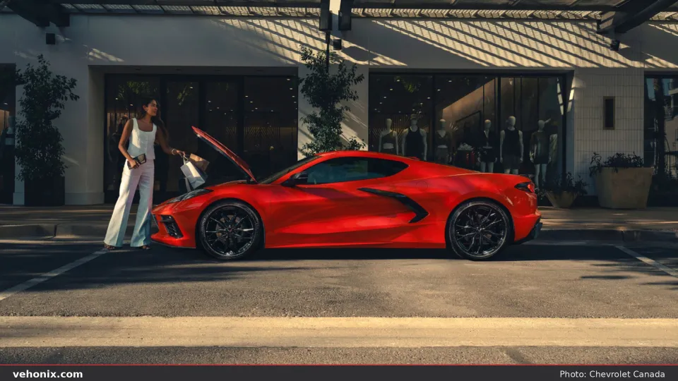 2026 Chevrolet Corvette in red, side profile with frunk open at a storefront