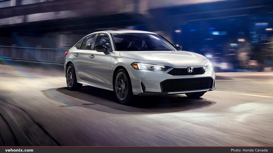 2026 Honda Civic Sport Hybrid in Solar Silver, front view driving under city lights