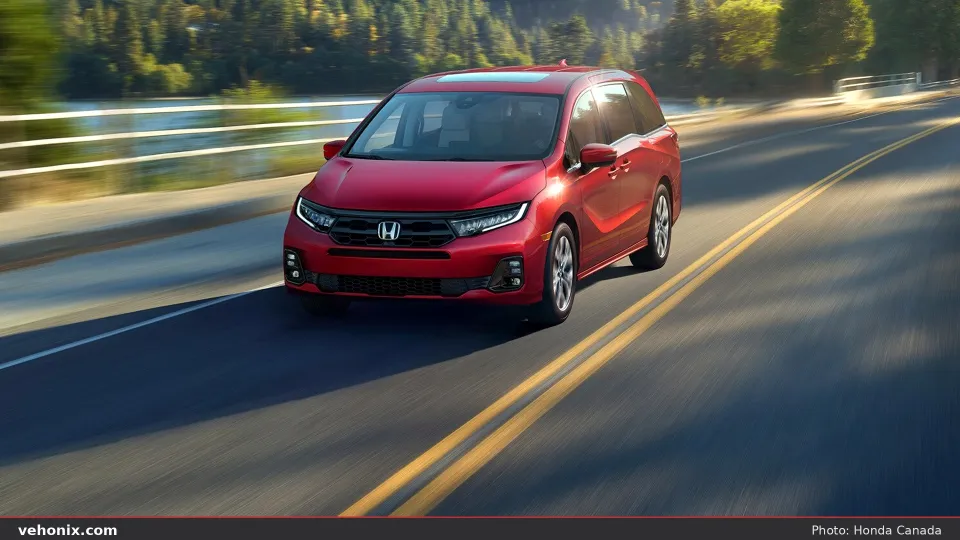 2026 Honda Odyssey Elite in Radiant Red Metallic, front view driving by water
