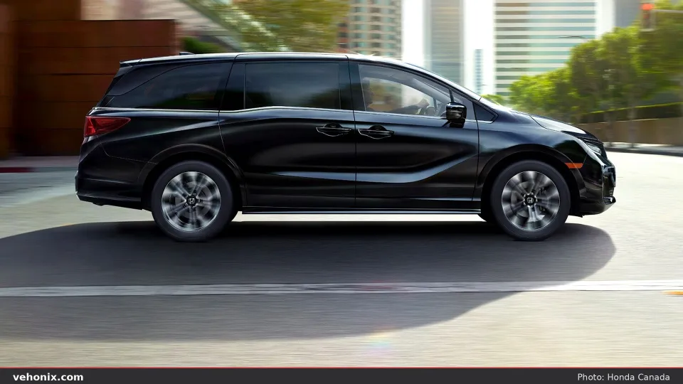 2026 Honda Odyssey Elite in Crystal Black Pearl, side profile driving in the city