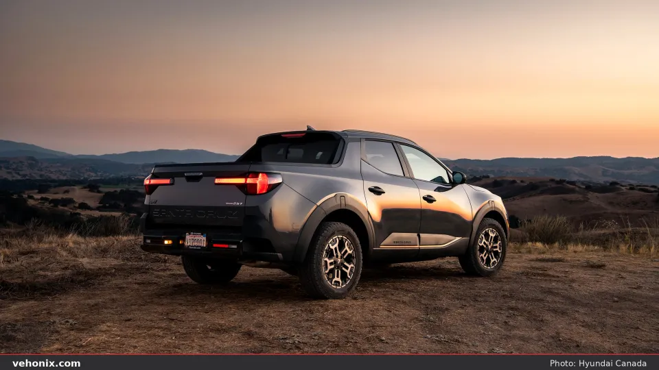2026 Hyundai Santa Cruz in dark grey, rear three-quarter in hilly terrain