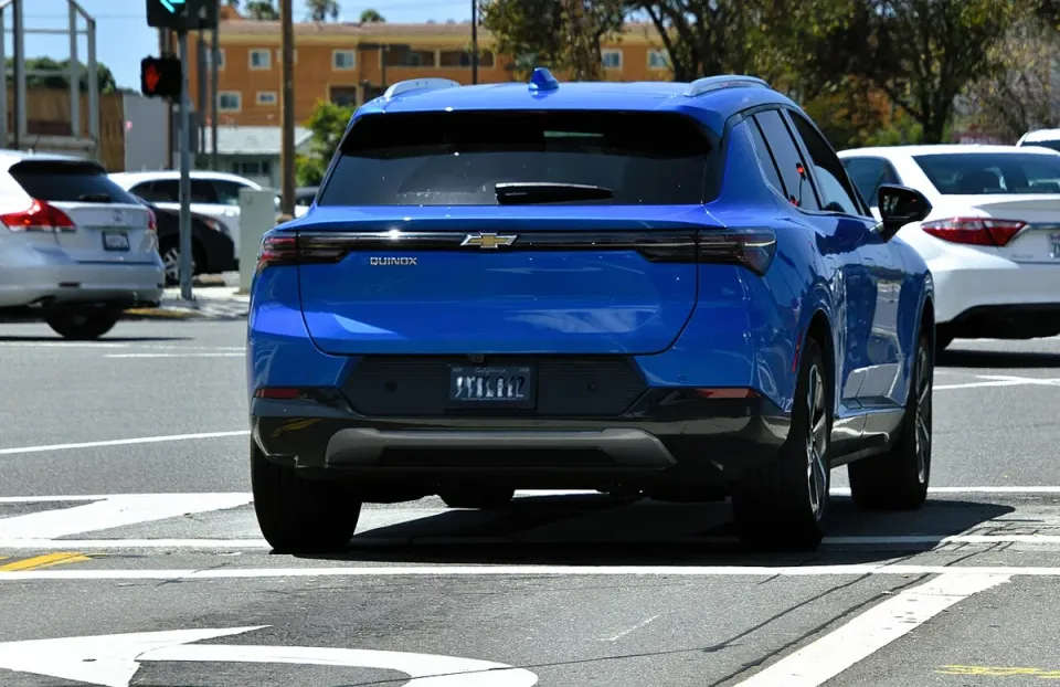 A blue Chevrolet Equinox EV seen from the back on a city street