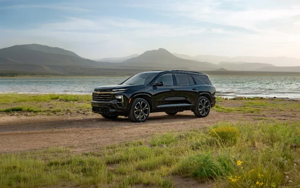 A black 2027 Chevrolet Traverse High Country three row SUV parked near a lake