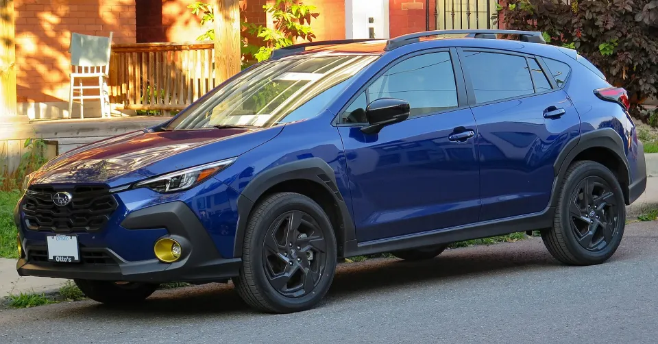 Blue 2024 Subaru Crosstrek Onyx with black wheels and yellow fog-lamp accents, parked on a street in Ottawa