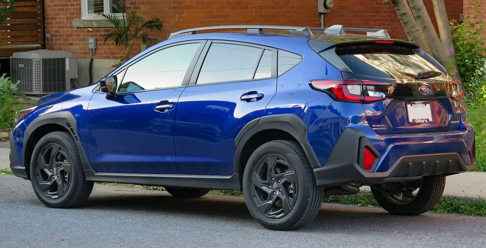 Rear three-quarter view of a blue 2024 Subaru Crosstrek Onyx with black alloy wheels and roof rails, parked in Ottawa