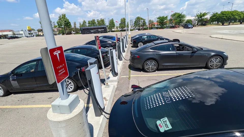 Several electric cars plugged into fast chargers in a parking lot in Canada
