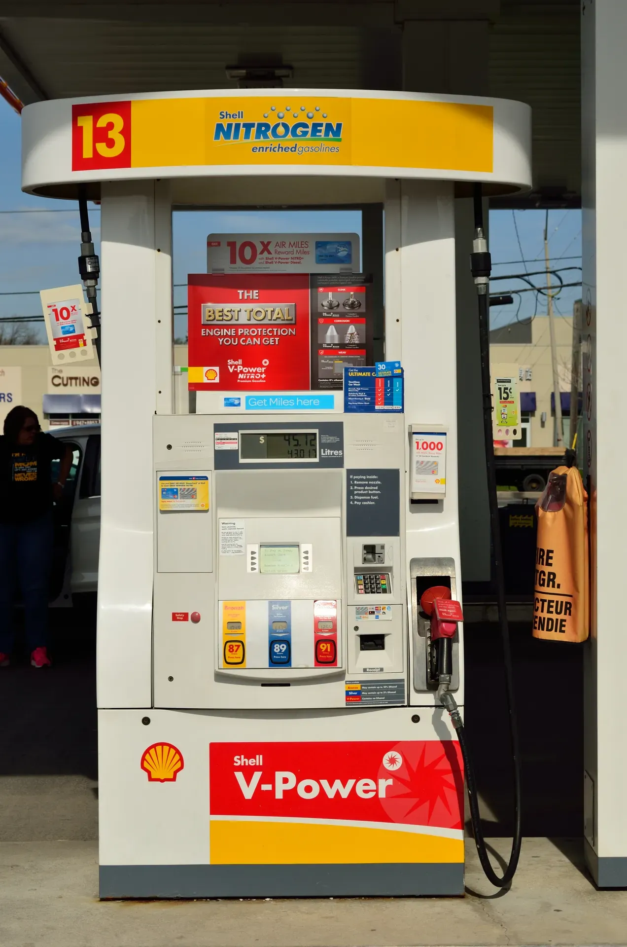 A gas pump with three fuel grade buttons and a nozzle hanging on the side