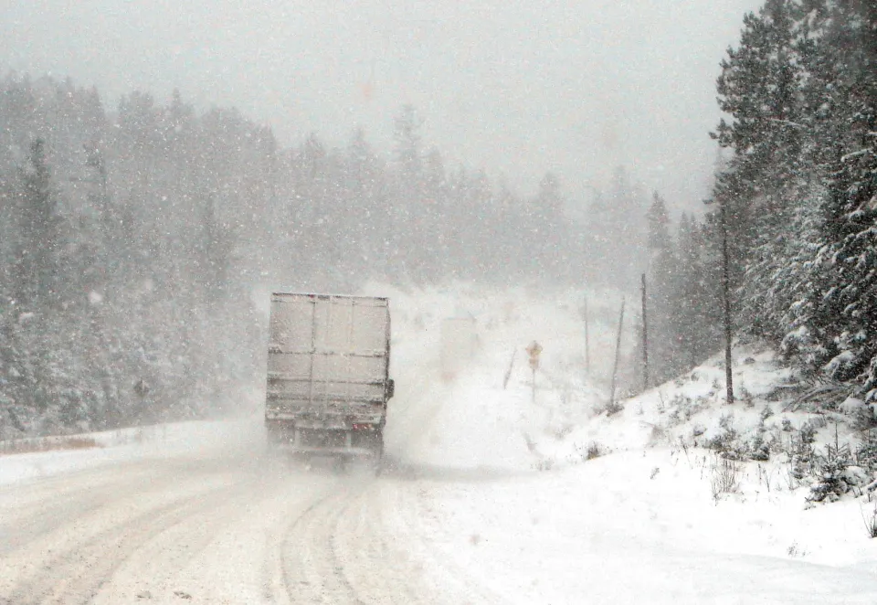 A large truck driving through a snowstorm on Highway 11 near Temagami, Ontario