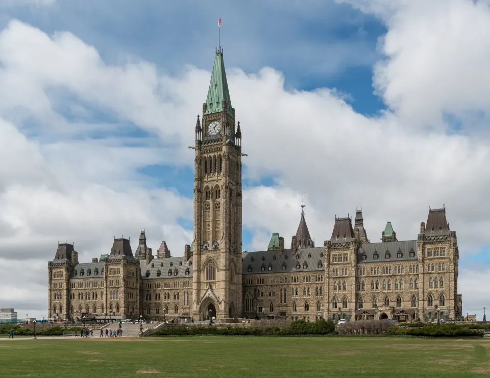 The Centre Block and Peace Tower on Parliament Hill in Ottawa under a cloudy blue sky