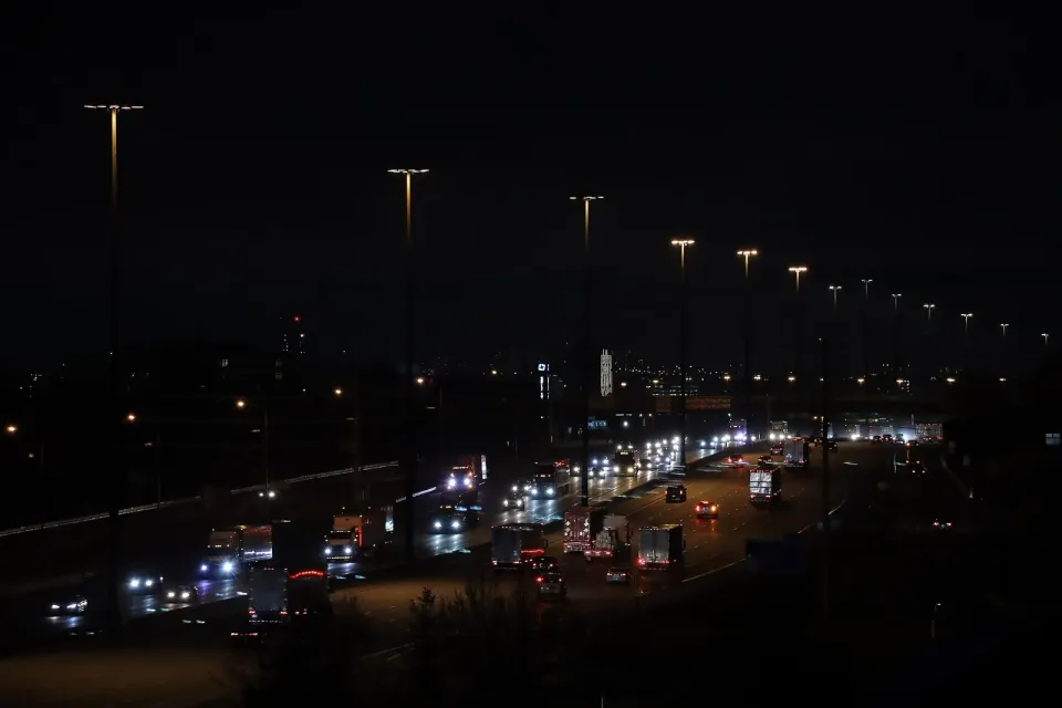 Night traffic with headlights and tail lights on Highway 401 west near Ajax, Ontario, under tall street lights