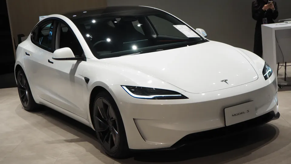 White Tesla Model 3 with updated Highland styling in a showroom, front three-quarter view