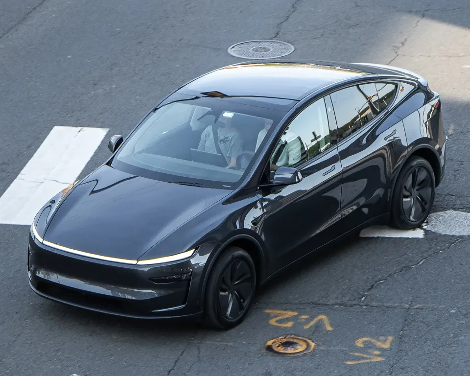Un Tesla Model Y 2026 gris foncé qui roule dans une rue de ville